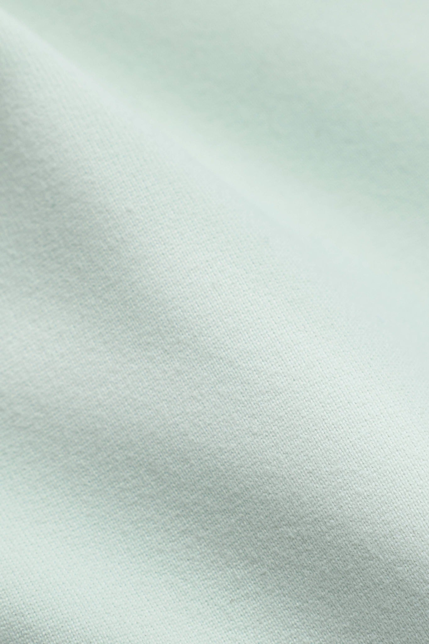 Close-up of pistachio green Sculptluxe fabric texture on a CASPARA jacket.